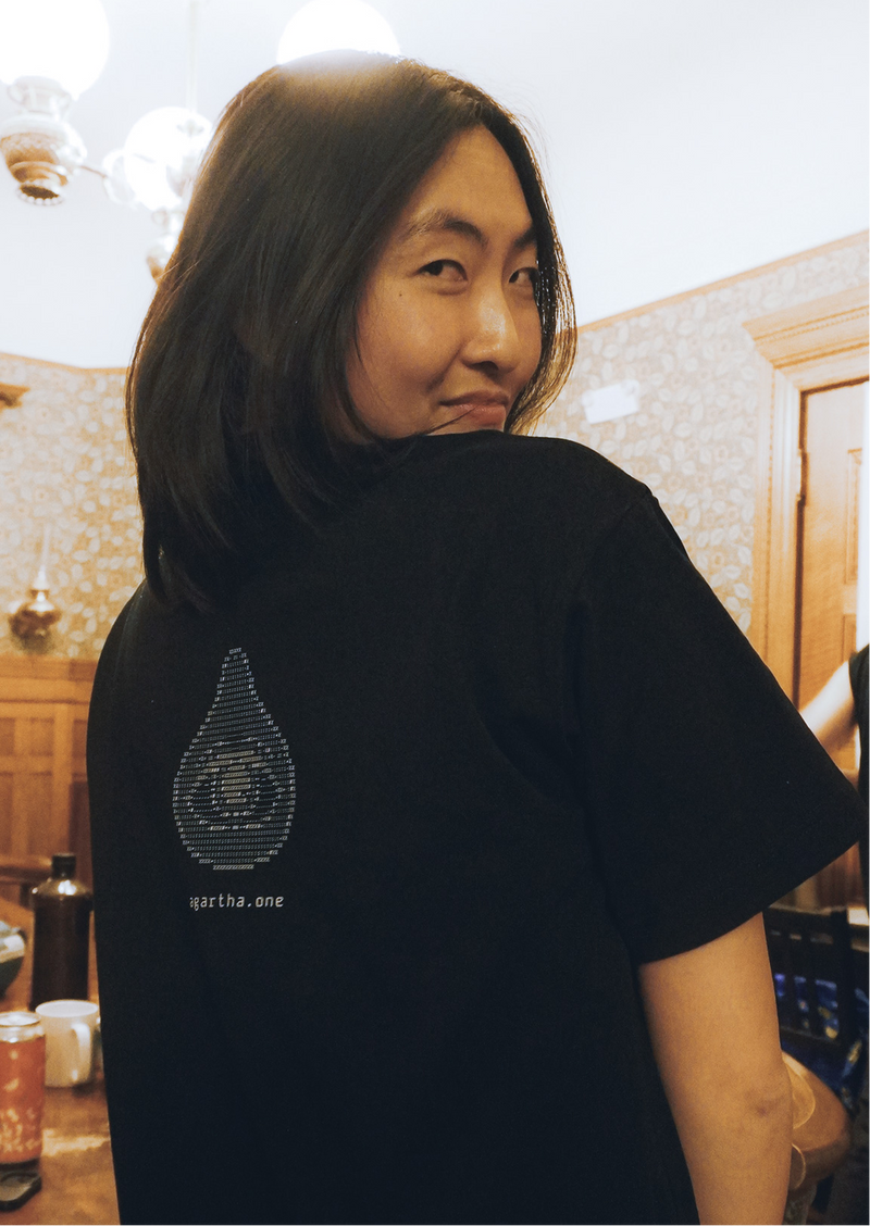 Person wearing a black t-shirt with a logo on the back, standing in a room with decorative elements.