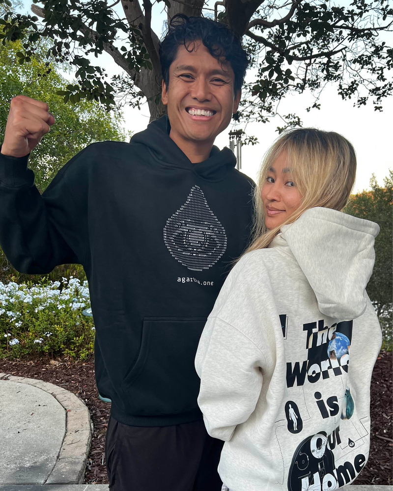 Two people wearing hoodies with visible text and graphics outdoors.